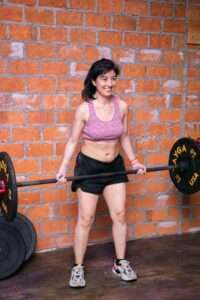 a woman with a barbell doing deadlift fitness exercise at a gym