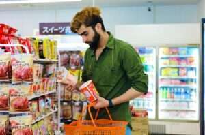 a man reading the label on a cup of noodles. This is how to stop sugar from destroying your health.