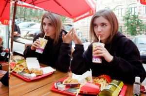 a woman eating processed food at MacDonald's. Another way how sugar destroys your health.