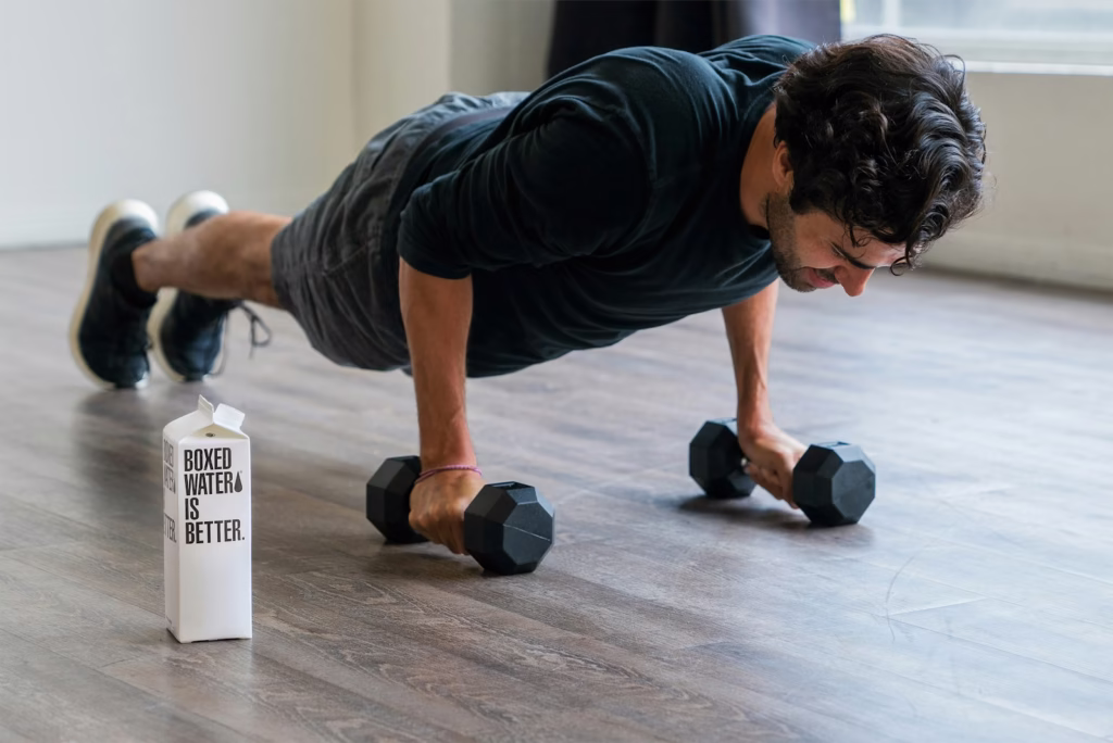 man in black t-shirt and black shorts doing push up with dumbbells